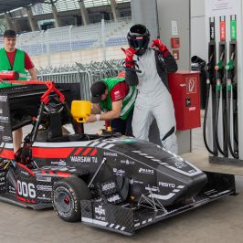 Na zdjęciu bolid oraz trzy stojące przy nim osoby