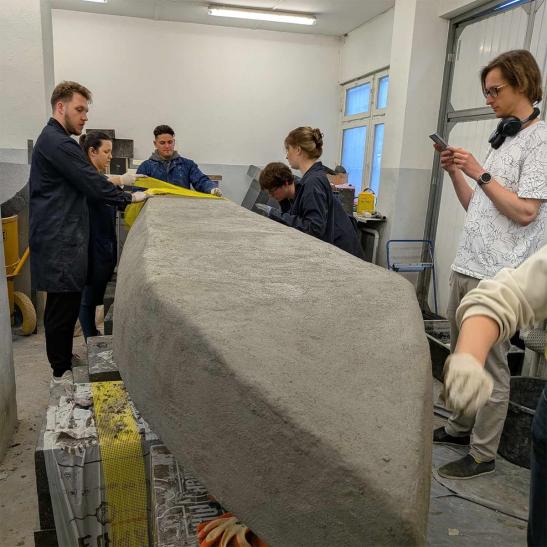 Na zdjęciu grupa osób pracująca nad kajakiem z betonu 