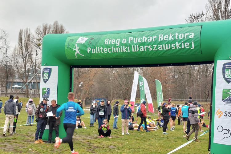 Na zdjęciu zawodnicy wbiegający na metę biegu z widocznym napisem Bieg o Puchar Rektora Politechniki Warszawskiej