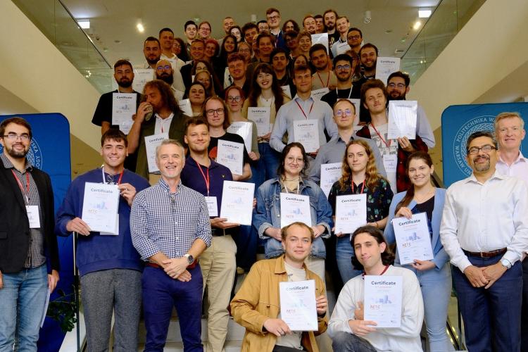 Na zdjęciu grupa kilkudziesiąciu osób stojących na schodach w Centrum Zaawansowanych Materiałów i Technologii PW CEZAMAT 