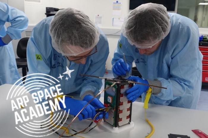 Zdjęcie dwóch osób pracujących nad budową satelity