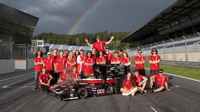 Na zdjęciu grupa studentów stojących na torze oraz bolid