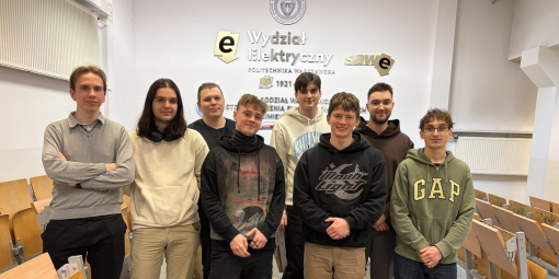 Zdjęcie przedstawia ośmiu studentów stojących na tle ściany z logotypem Wydziału Elektrycznego PW