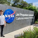 Doktorant PW, Damian Grabowski, stoi obok logotypu NASA i JPL w Kalifornijskim Instytucie Technicznym