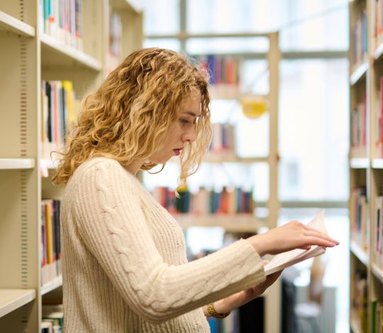 Studentka przeglądająca zbiory biblioteczne